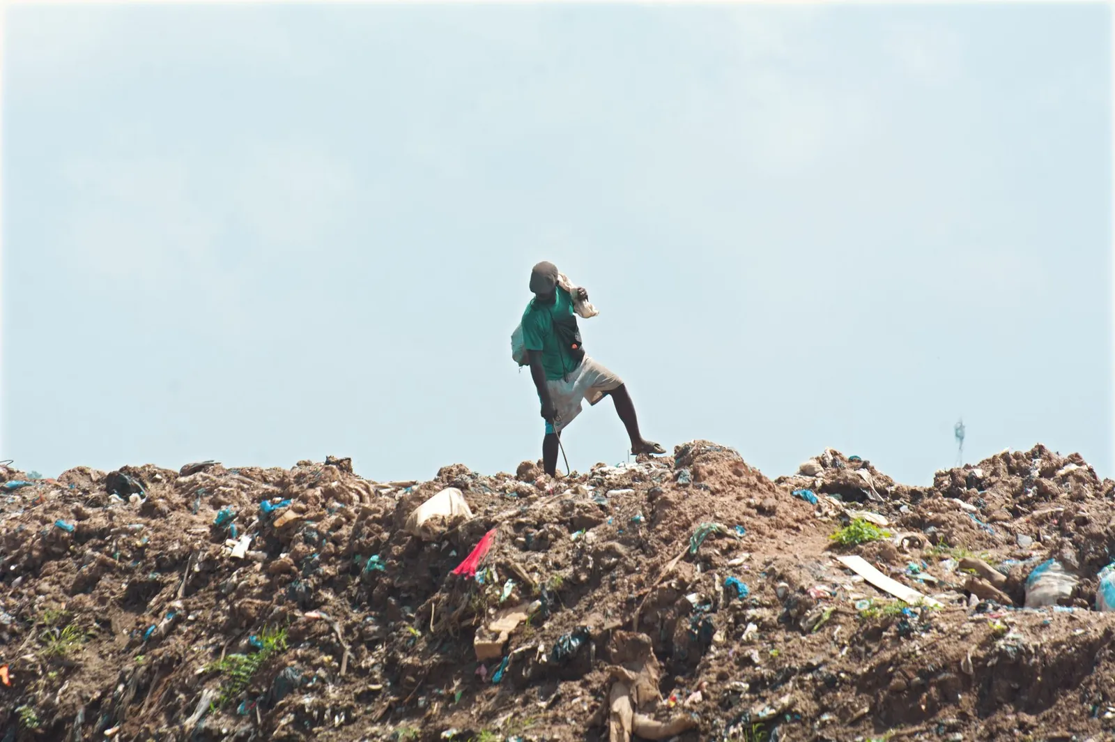 A waste picker walking across an open landfill site in Ghana